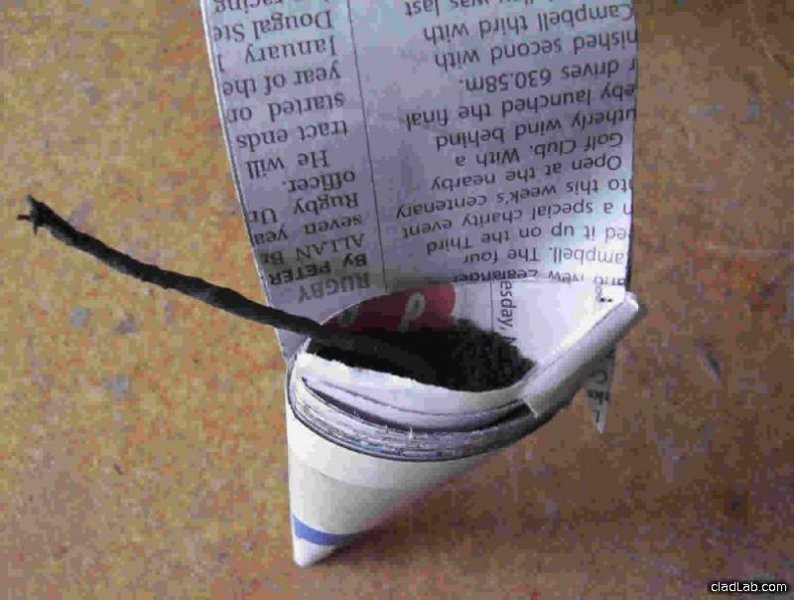 Wrapping the newspaper into a triangle, filling it with blackpower, and then adding a fuse.
