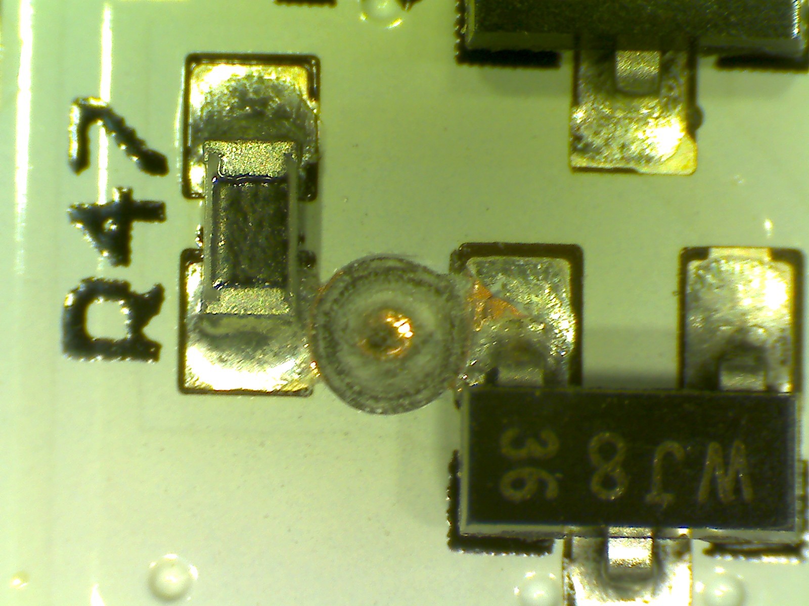 A drilled-out via (to break the connection) between a 0603 resistor and SOT-23-3 MOSFET.