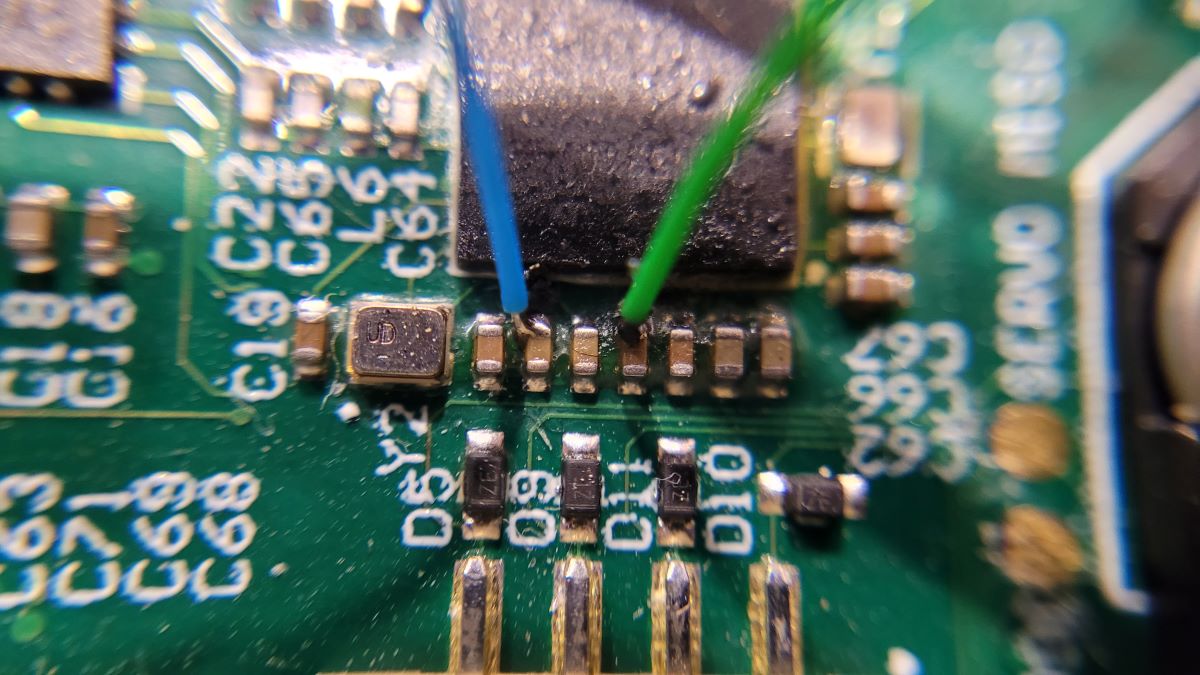 Picture of two wires soldered onto the XX and XX pins of a bricked Nordic nRF5340-QKAAD0 MCU so that the internal voltage rails can be provided by external power supplies.